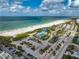 Aerial beach scene with a public pool, parking, and a sandy shoreline near condo buildings at 800 S Blvd Of Presidents # 12, Sarasota, FL 34236