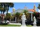 Elegant building exterior with a red tile roof, white statues, palm trees and parked cars under a clear blue sky at 800 S Blvd Of Presidents # 12, Sarasota, FL 34236