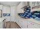 A modern kitchen with white cabinetry, stainless steel appliances, and a stylish blue backsplash at 2028 Woodleaf Hammock Ct, Bradenton, FL 34211