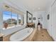 Luxurious primary bathroom with soaking tub, dual vanity, and large window with a view at 550 Yardarm Ln, Longboat Key, FL 34228