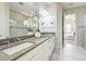 Bathroom featuring double sinks, white cabinetry, a large mirror, and a view into the bedroom at 12826 Sorrento Way, Bradenton, FL 34211
