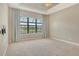 Comfortable carpeted bedroom featuring a ceiling fan, large window, and neutral color palette at 4020 Cascina Way, Sarasota, FL 34238
