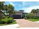 Charming single-Gathering home featuring lush landscaping, a brick driveway, and a two-car garage at 4020 Cascina Way, Sarasota, FL 34238