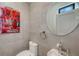 Modern powder room featuring gray tiled walls, a round mirror, and an artistic painting at 1774 10Th St, Sarasota, FL 34236