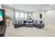 Bright living room with a large sofa, gray ottoman, large windows, carpeted floor, and modern lighting at 13891 Heartwood Way, Parrish, FL 34219