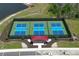Aerial view of pickleball courts featuring a red canopy and surrounded by a black fence and lush landscaping at 8684 Canyon Creek Trl, Parrish, FL 34219