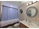Cozy bathroom with stylish round mirror, vanity, and shower with attractive curtain at 9606 Sea Turtle Ter # 101, Bradenton, FL 34212