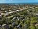 Aerial view of a neighborhood with lush trees, blue sky, and ocean in the distance at 304 Pine Run Dr, Osprey, FL 34229
