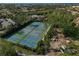 Aerial view of well-maintained tennis courts surrounded by lush greenery at 304 Pine Run Dr, Osprey, FL 34229