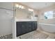 Bathroom featuring a walk-in shower, dual sink vanity, and soaking tub beneath a window at 727 Holly Rd, Anna Maria, FL 34216