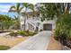 Charming two-story home with lush landscaping, palm trees, and a spacious driveway at 727 Holly Rd, Anna Maria, FL 34216