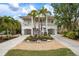 Beautiful two-story home with a well-manicured lawn, tropical plants, and a spacious driveway at 727 Holly Rd, Anna Maria, FL 34216