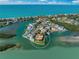 Aerial view of waterfront home with lush landscaping, private dock, and pool on peninsula, surrounded by turquoise water at 929 Casey Cove Dr, Nokomis, FL 34275