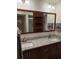 Bathroom featuring double sink, granite countertop, wooden cabinets and framed mirrors with shelves at 2098 35Th N St, St Petersburg, FL 33713