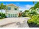 Charming two-story home featuring a beautifully landscaped front yard, a brick driveway, and an attached two-car garage at 213 84Th St, Holmes Beach, FL 34217