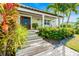 Charming front porch with a wood door, complemented by lush tropical landscaping and a brick walkway at 213 84Th St, Holmes Beach, FL 34217