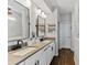 Bathroom with double sink, white cabinets, framed mirrors, floating shelves, and modern fixtures at 3409 Anchor Bay Trl, Lakewood Ranch, FL 34211