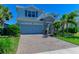 Two-story home boasts a stone-accented entrance, a two-car garage, and a brick paved driveway, complemented by lush landscaping at 3409 Anchor Bay Trl, Lakewood Ranch, FL 34211