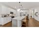 Bright, modern kitchen with white cabinetry, stainless steel appliances, a large island with seating, and hardwood flooring at 3409 Anchor Bay Trl, Lakewood Ranch, FL 34211