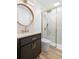 Bathroom features a glass-enclosed shower, dark vanity, round mirror, and modern fixtures at 4536 1St N Ave, St Petersburg, FL 33713