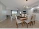 Dining area with wooden table and six upholstered chairs, flowing into the living room with plenty of natural light at 8402 Grand Estuary Trl # 101, Bradenton, FL 34212