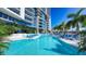 Relaxing pool area with blue lounge chairs and umbrellas next to a modern building and palm trees at 1155 N Gulfstream Ave # 607, Sarasota, FL 34236