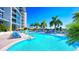 Pool with blue lounge chairs, umbrellas, and palm trees with the building in the background at 1155 N Gulfstream Ave # 607, Sarasota, FL 34236
