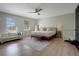 Cozy main bedroom features wood floors, ceiling fan, sitting area, and natural light from two windows at 12001 Backwater Rd, Sarasota, FL 34240