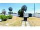 Landscaped backyard with palm trees, a grill, storage shed, and white privacy fence at 241 Seminole Nw Blvd, Port Charlotte, FL 33952