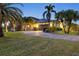 Beautiful home exterior at dusk with a circular driveway and lush tropical landscaping at 3607 Darin Dr, Punta Gorda, FL 33950