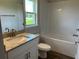 Bathroom with granite countertop, white cabinets, and tiled shower at 2648 Averland Loop, North Port, FL 34287