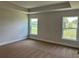 Spacious bedroom with neutral carpet, tray ceiling, and windows overlooking the lawn at 2648 Averland Loop, North Port, FL 34287