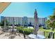 Condo's outdoor patio area offering tables, chairs, umbrellas and views of the building's facade at 5740 Midnight Pass Rd # 307, Sarasota, FL 34242