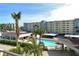Exterior building view with swimming pool, palm trees, and covered parking at 5740 Midnight Pass Rd # 307, Sarasota, FL 34242