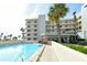 Exterior view of building and pool with lounge area, palm trees, and walkway at 5740 Midnight Pass Rd # 307, Sarasota, FL 34242