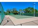 Well-maintained tennis court with green fencing surrounded by mature trees and clear blue skies at 5740 Midnight Pass Rd # 307, Sarasota, FL 34242