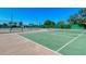 Outdoor tennis courts with green surface surrounded by a fence and lush greenery on a clear, sunny day at 5740 Midnight Pass Rd # 307, Sarasota, FL 34242