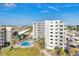 Bright, airy, white condo building with a community pool and tropical landscaping under a sunny blue sky at 5830 Midnight Pass Rd # 502, Sarasota, FL 34242