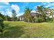 Expansive backyard featuring lush green grass, tropical trees and plants at 6630 Horned Owl Pl, Sarasota, FL 34241