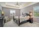 Cozy bedroom featuring plush carpeting, tray ceiling, neutral colors, and natural light at 6630 Horned Owl Pl, Sarasota, FL 34241