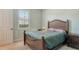 This cozy bedroom features a wood frame bed, a window with shutters, and soft, neutral paint at 6630 Horned Owl Pl, Sarasota, FL 34241