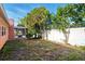 A partly grassy backyard with mature trees and white fencing at 1741 Font Ln, Holiday, FL 34691