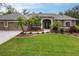 Charming home featuring a lush green lawn, mature palm trees, and meticulous landscaping, enhancing its curb appeal at 3826 E 155Th E Ave, Parrish, FL 34219