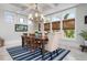 Elegant dining room with large windows, a chandelier, and a stylish blue striped rug at 718 Key Royale Dr, Holmes Beach, FL 34217