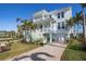 Charming three-story home showcasing multiple balconies, a lush front yard, driveway, and tropical landscaping at 718 Key Royale Dr, Holmes Beach, FL 34217
