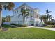Two-story beach home with multiple decks and a lush green lawn surrounded by palm trees and tropical plants at 718 Key Royale Dr, Holmes Beach, FL 34217
