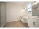 Spacious bathroom with a glass-enclosed shower and dual vanities, featuring wood-look flooring at 8528 Beechlake Ct, Sarasota, FL 34240