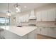 Stylish kitchen boasts sleek white cabinets, stainless steel appliances, a large island, and modern pendant lights at 8528 Beechlake Ct, Sarasota, FL 34240