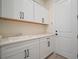 Bright laundry room with white cabinets, dark hardware, quartz countertop, and convenient utility sink at 8528 Beechlake Ct, Sarasota, FL 34240