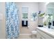 Bright bathroom with a patterned shower curtain, white vanity, neutral paint, and decorative accents at 11728 Meadowgate Pl, Bradenton, FL 34211